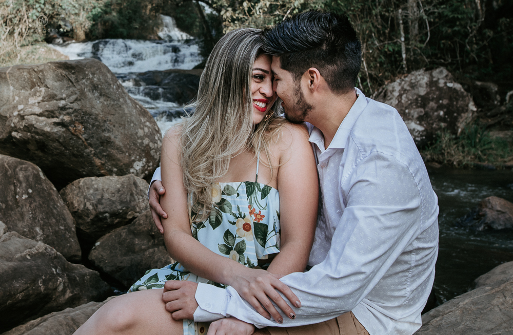 Ensaio casal pre-wedding na cachoeira com céu azul no entardecer.