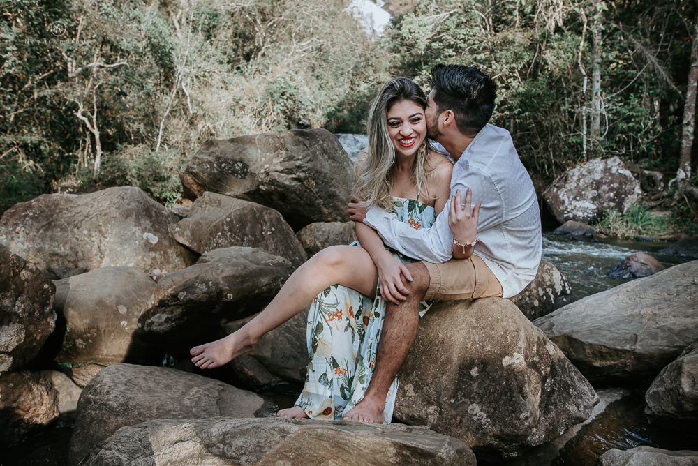 Ensaio casal pre-wedding na cachoeira com céu azul no entardecer.