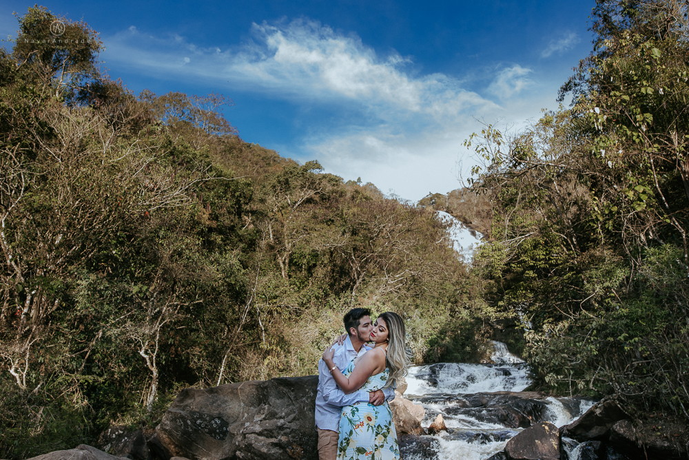 Ensaio casal pre-wedding na cachoeira com céu azul no entardecer.