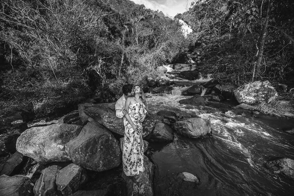 Ensaio casal pre-wedding na cachoeira com céu azul no entardecer.