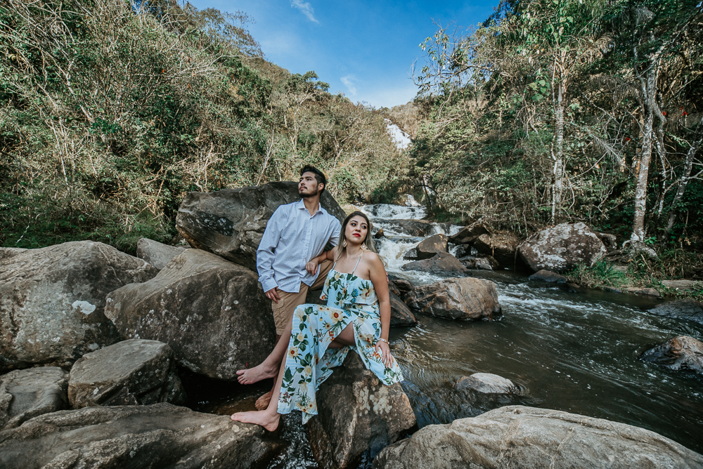 Ensaio casal pre-wedding na cachoeira com céu azul no entardecer.