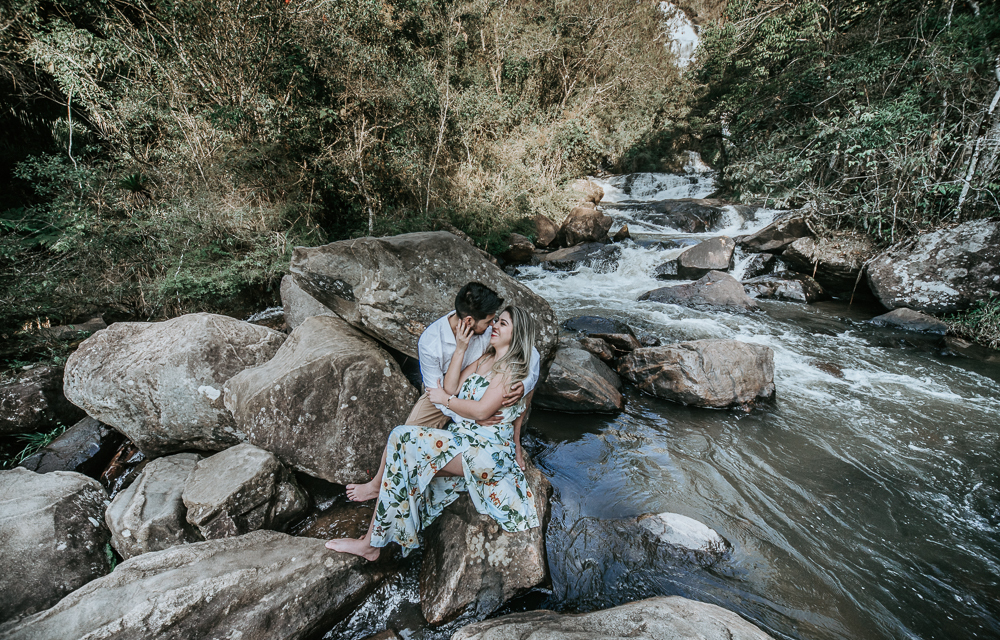 Ensaio casal pre-wedding na cachoeira com céu azul no entardecer.