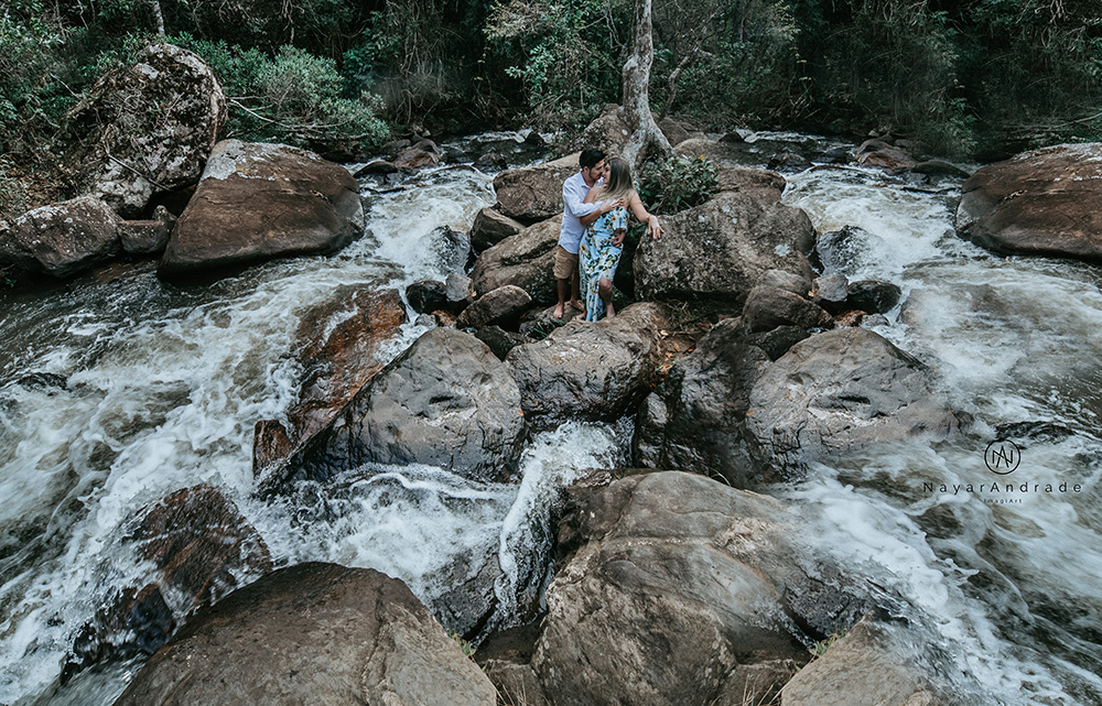 Ensaio casal pre-wedding na cachoeira com céu azul no entardecer.