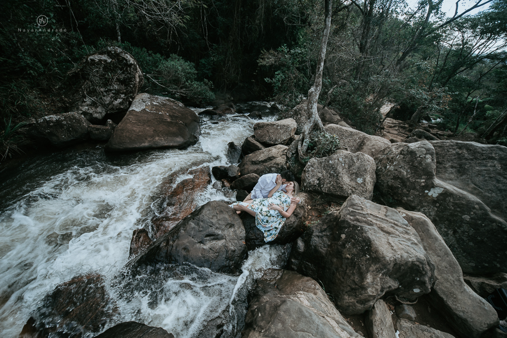 Ensaio casal pre-wedding na cachoeira com céu azul no entardecer.
