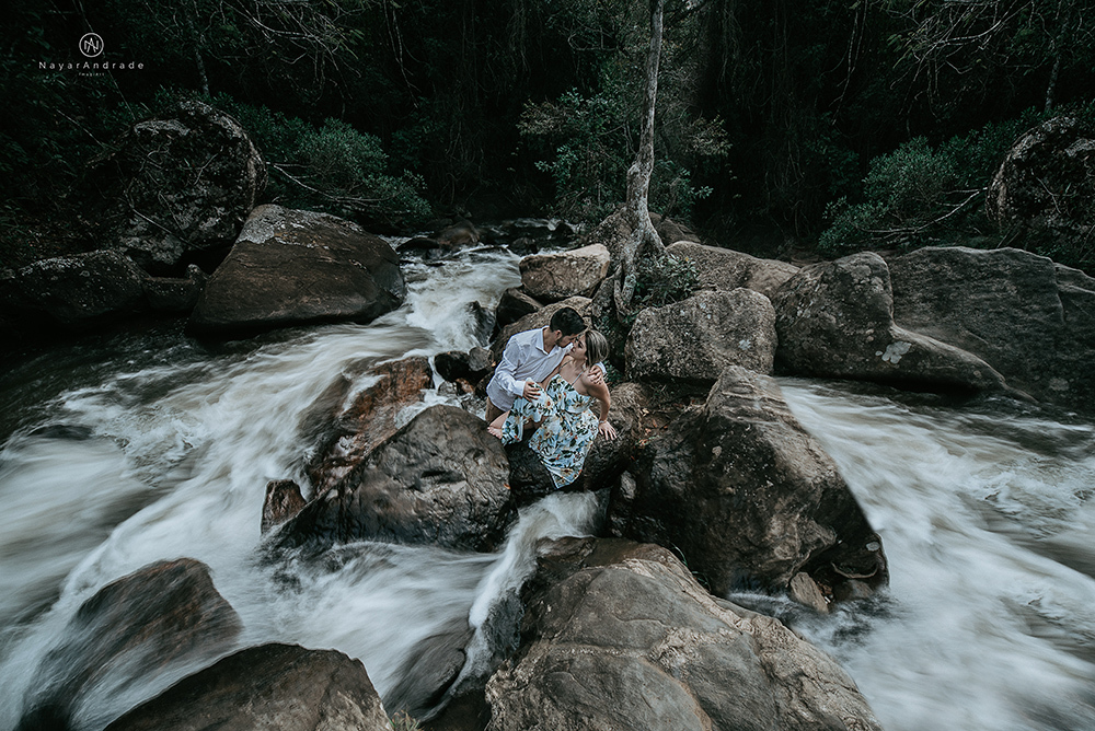 Ensaio casal pre-wedding na cachoeira com céu azul no entardecer.
