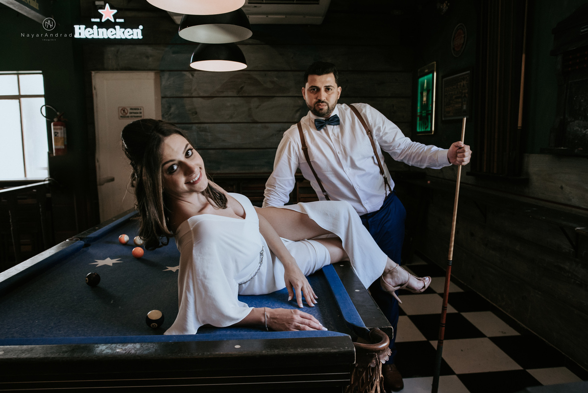 Mini wedding em Santos no australiano bar, noiva com vestido longo de fenda e noivo de suspensorio e gravata borboleta. Fotos de casamento na mesa de sinucae no bar. Casal apaixonado em mini wedd de manha