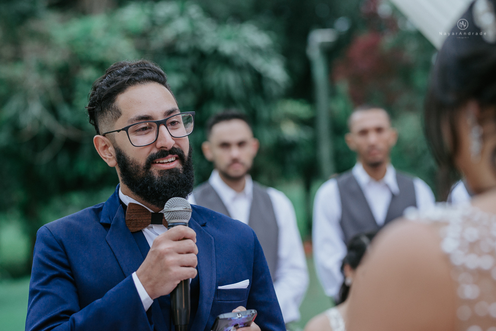 casamento ao ar livre de dia com noiva princesa e noivo de terno azul e gravata borboleta de madeira decoracao com guirlanda e padrinhos com balao de coracao