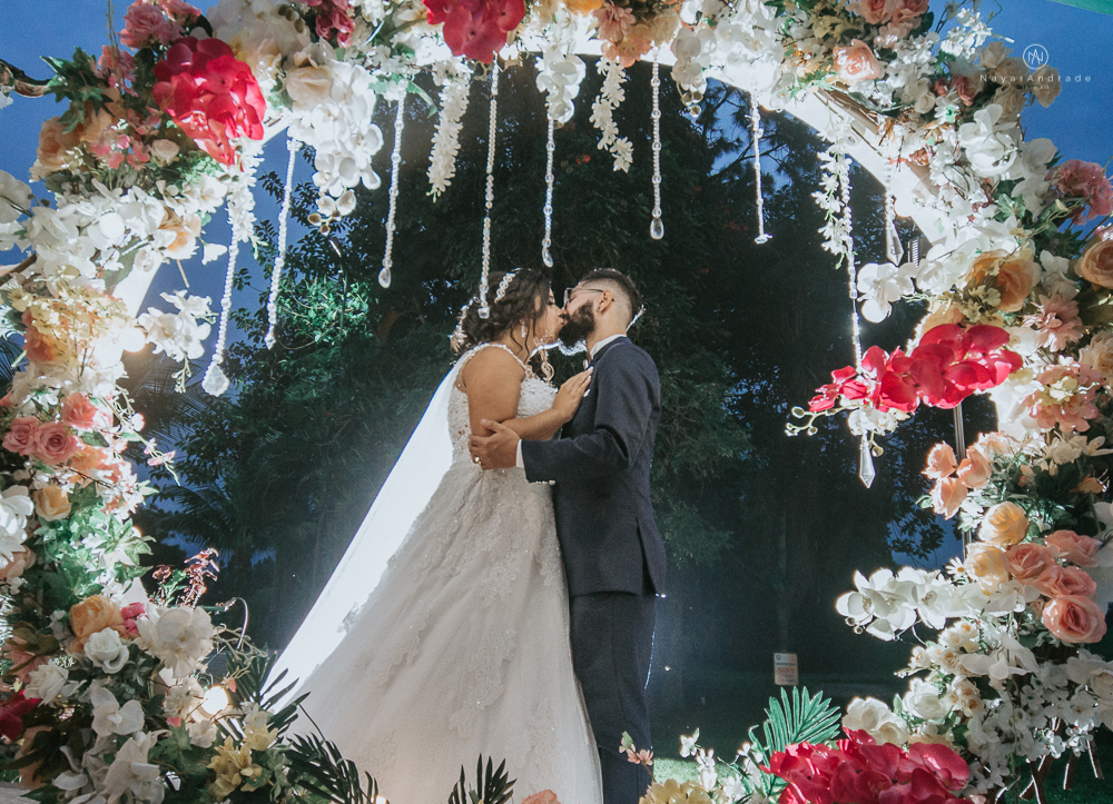 casamento ao ar livre de dia com noiva princesa e noivo de terno azul e gravata borboleta de madeira decoracao com guirlanda e padrinhos com balao de coracao