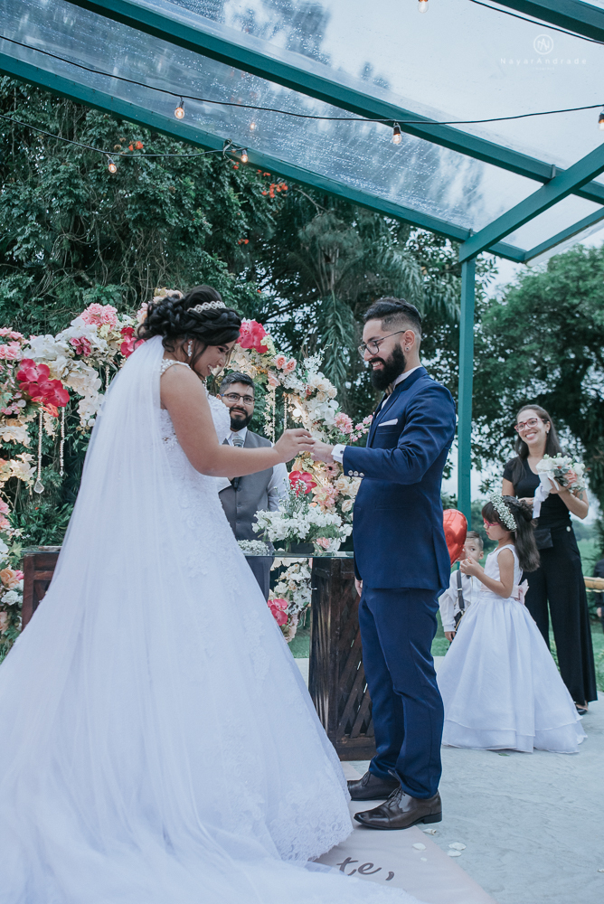 casamento ao ar livre de dia com noiva princesa e noivo de terno azul e gravata borboleta de madeira decoracao com guirlanda e padrinhos com balao de coracao