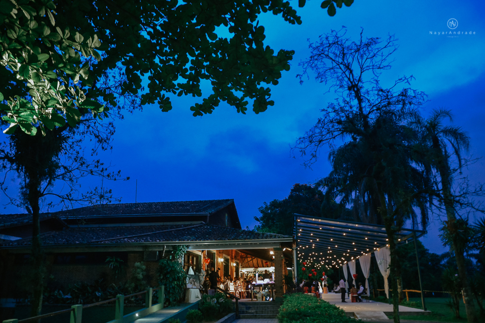 casamento ao ar livre de dia com noiva princesa e noivo de terno azul e gravata borboleta de madeira decoracao com guirlanda e padrinhos com balao de coracao