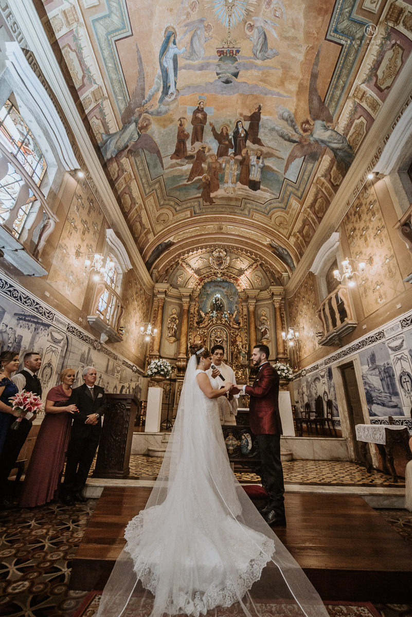 casamento classico noivo com terno marsala e noiva com mantilha no santuario de santo antonio do valongo em santos fotos feitas com o por do sol pela fotografa premiada nayara andrade de santos