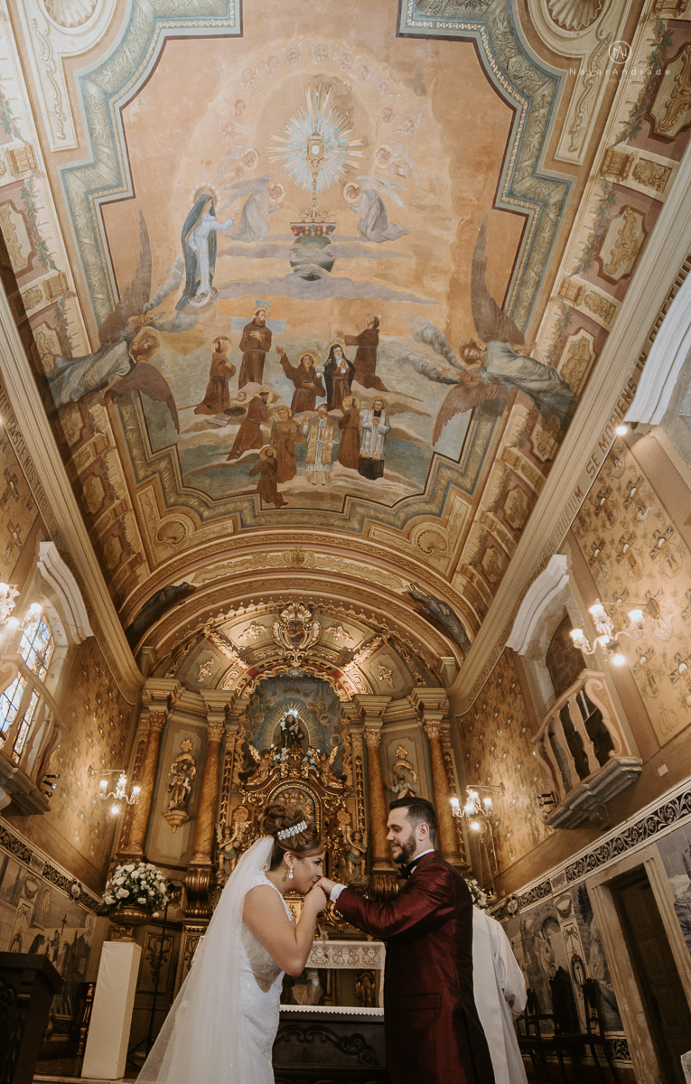casamento classico noivo com terno marsala e noiva com mantilha no santuario de santo antonio do valongo em santos fotos feitas com o por do sol pela fotografa premiada nayara andrade de santos