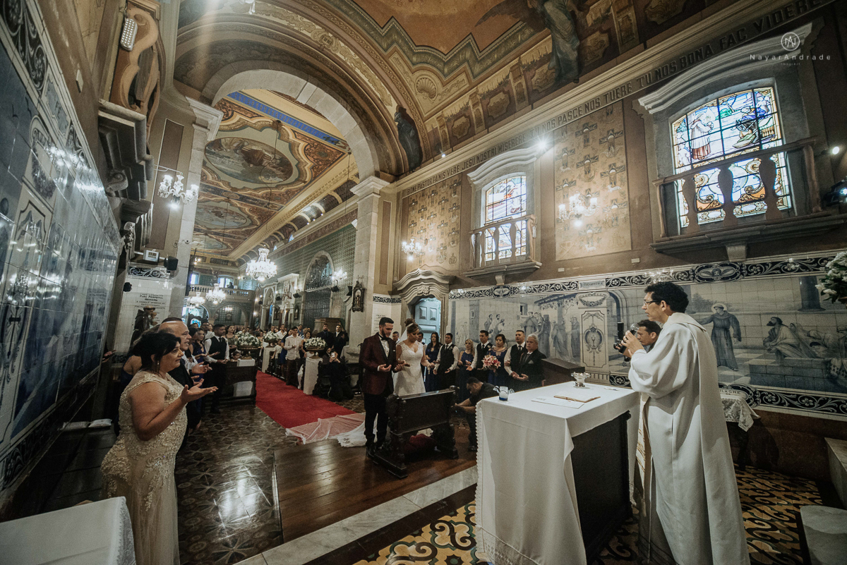 casamento classico noivo com terno marsala e noiva com mantilha no santuario de santo antonio do valongo em santos fotos feitas com o por do sol pela fotografa premiada nayara andrade de santos