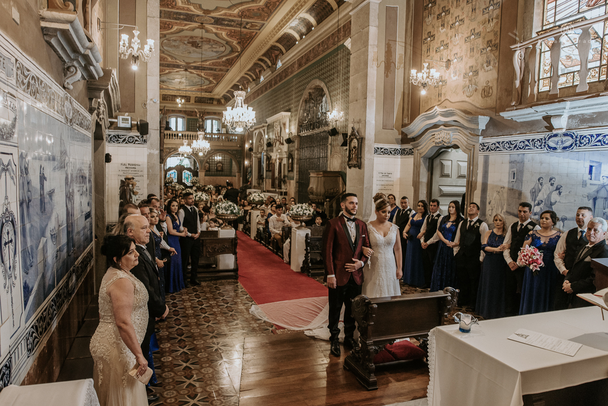 casamento classico noivo com terno marsala e noiva com mantilha no santuario de santo antonio do valongo em santos fotos feitas com o por do sol pela fotografa premiada nayara andrade de santos