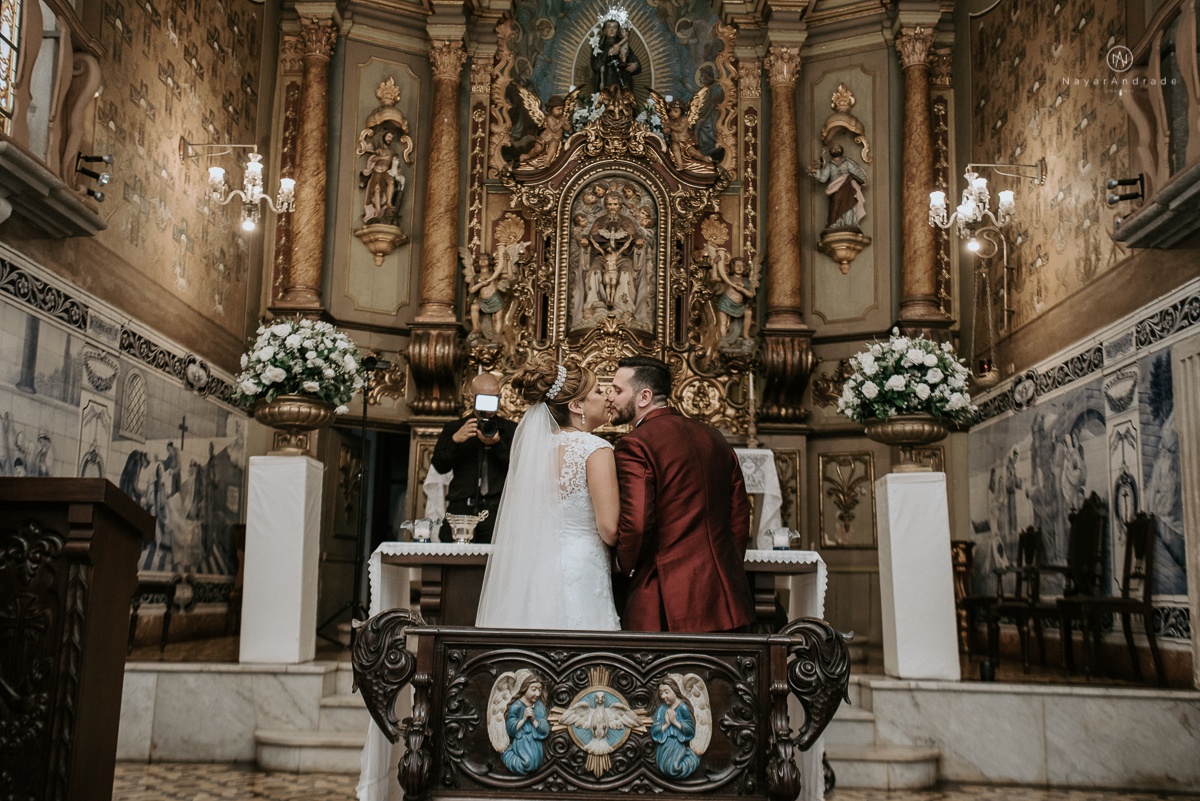 casamento classico noivo com terno marsala e noiva com mantilha no santuario de santo antonio do valongo em santos fotos feitas com o por do sol pela fotografa premiada nayara andrade de santos
