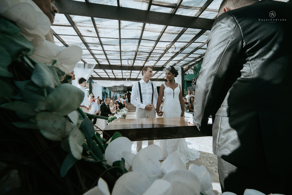 casamento italobrasileiro entre italiano e brasileira em lugar rustico ao ar livre de dia em clima descontraido noivo de all star noivo loiro e noiva negra tema com uvas e italia