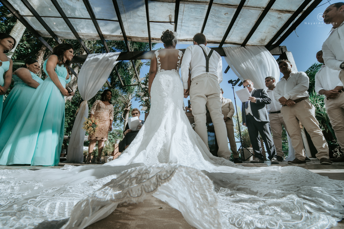 casamento italobrasileiro entre italiano e brasileira em lugar rustico ao ar livre de dia em clima descontraido noivo de all star noivo loiro e noiva negra tema com uvas e italia