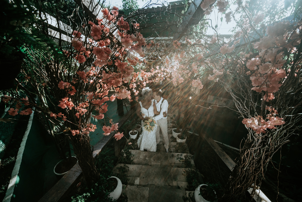 casamento italobrasileiro entre italiano e brasileira em lugar rustico ao ar livre de dia em clima descontraido noivo de all star noivo loiro e noiva negra tema com uvas e italia