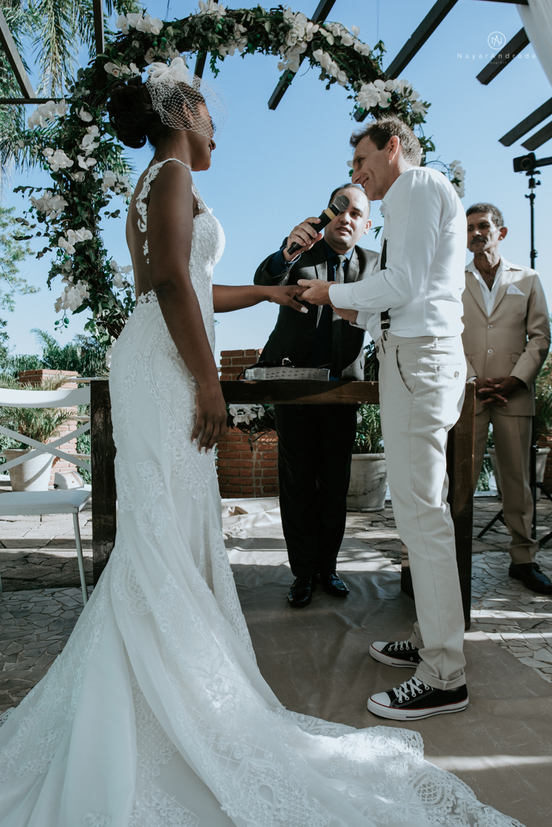 casamento italobrasileiro entre italiano e brasileira em lugar rustico ao ar livre de dia em clima descontraido noivo de all star noivo loiro e noiva negra tema com uvas e italia