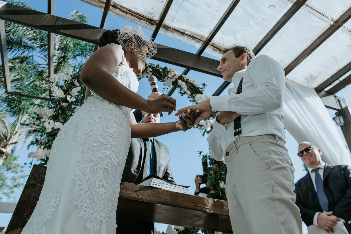 casamento italobrasileiro entre italiano e brasileira em lugar rustico ao ar livre de dia em clima descontraido noivo de all star noivo loiro e noiva negra tema com uvas e italia