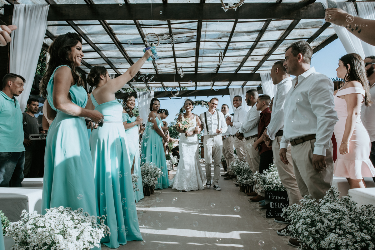 casamento italobrasileiro entre italiano e brasileira em lugar rustico ao ar livre de dia em clima descontraido noivo de all star noivo loiro e noiva negra tema com uvas e italia