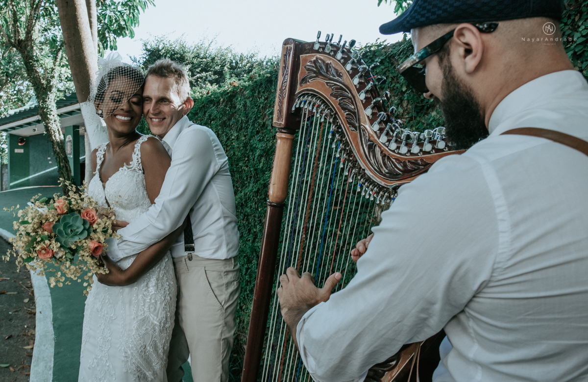 casamento italobrasileiro entre italiano e brasileira em lugar rustico ao ar livre de dia em clima descontraido noivo de all star noivo loiro e noiva negra tema com uvas e italia