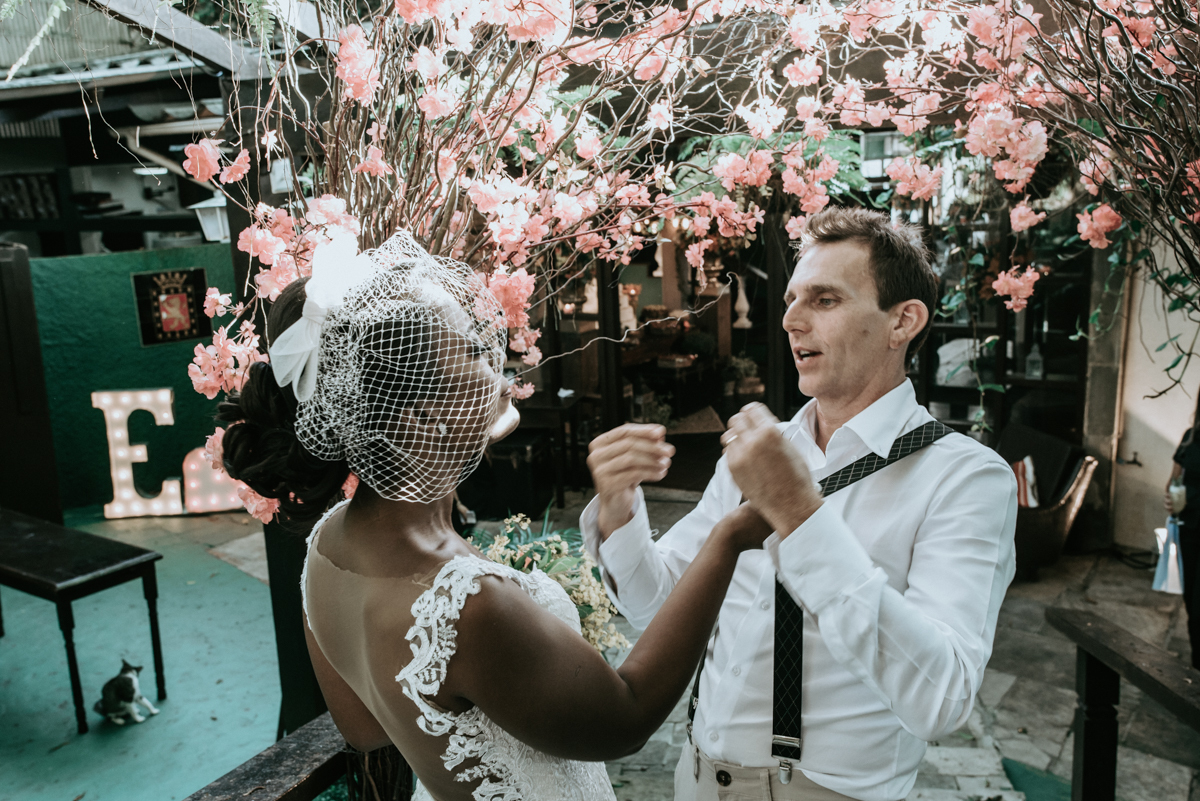 casamento italobrasileiro entre italiano e brasileira em lugar rustico ao ar livre de dia em clima descontraido noivo de all star noivo loiro e noiva negra tema com uvas e italia