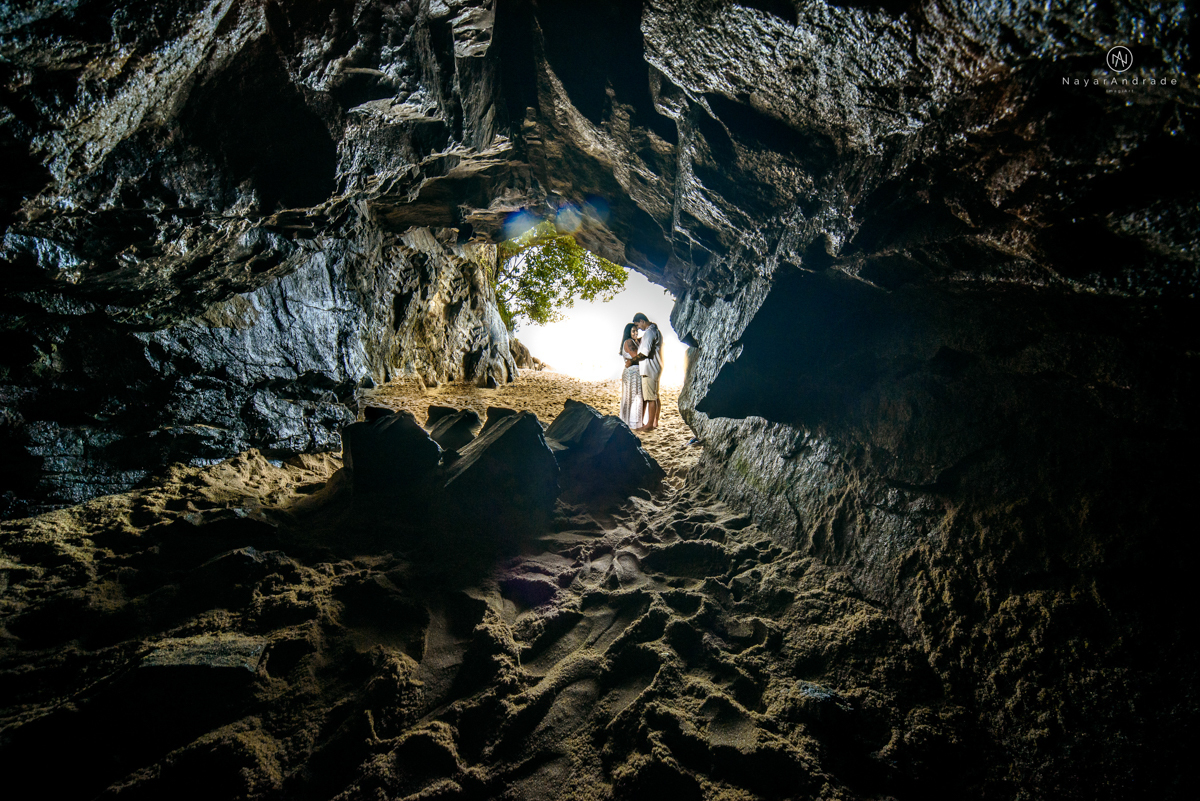 ensaio pre casamento na praia de ubatuba em sao paulo casal de blusa branca com fotos nas pedras e na agua cristalina