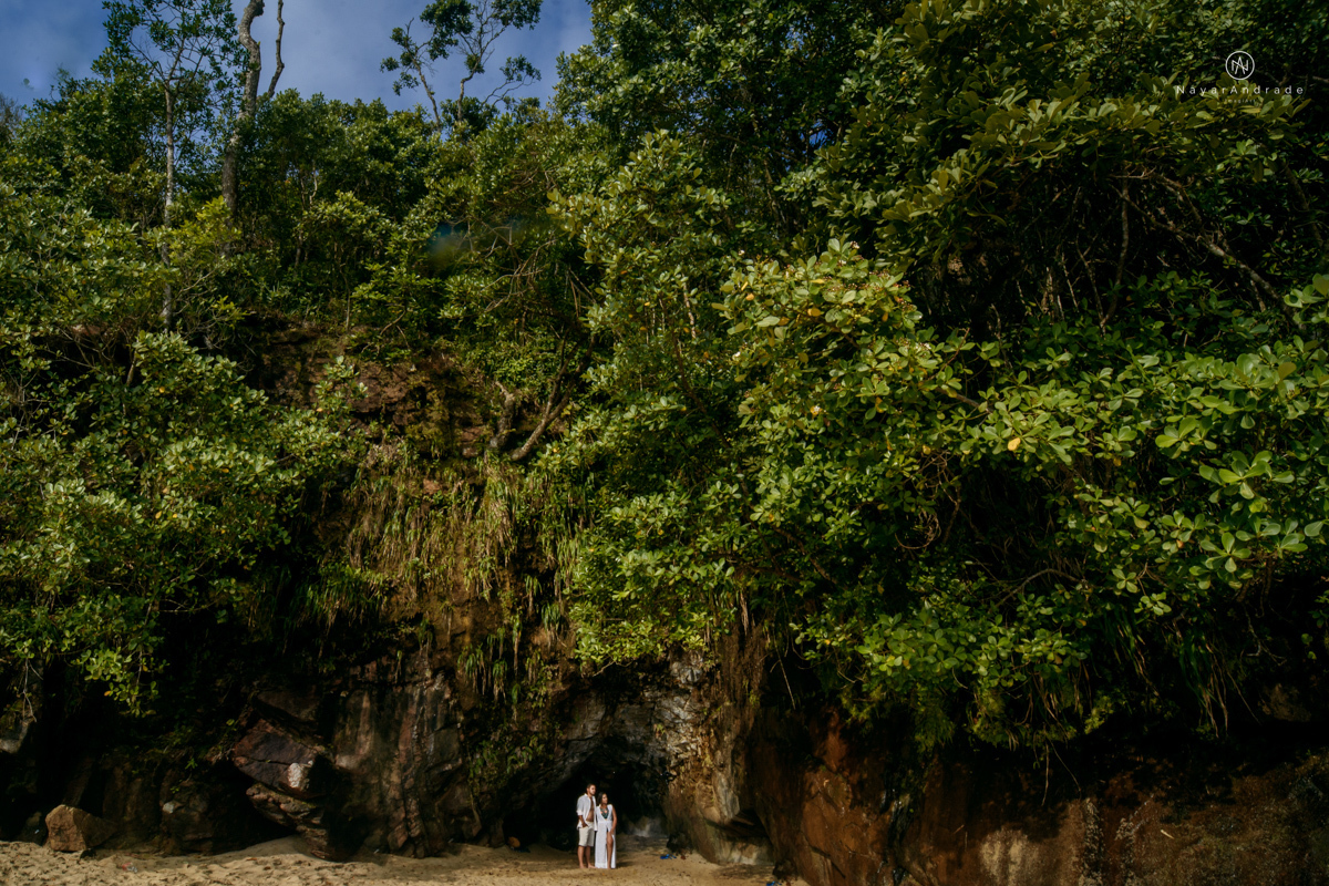 ensaio pre casamento na praia de ubatuba em sao paulo casal de blusa branca com fotos nas pedras e na agua cristalina