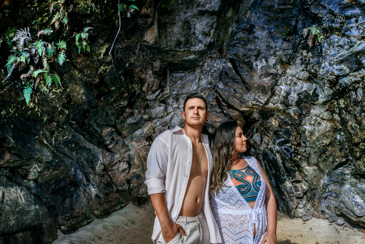 ensaio pre casamento na praia de ubatuba em sao paulo casal de blusa branca com fotos nas pedras e na agua cristalina