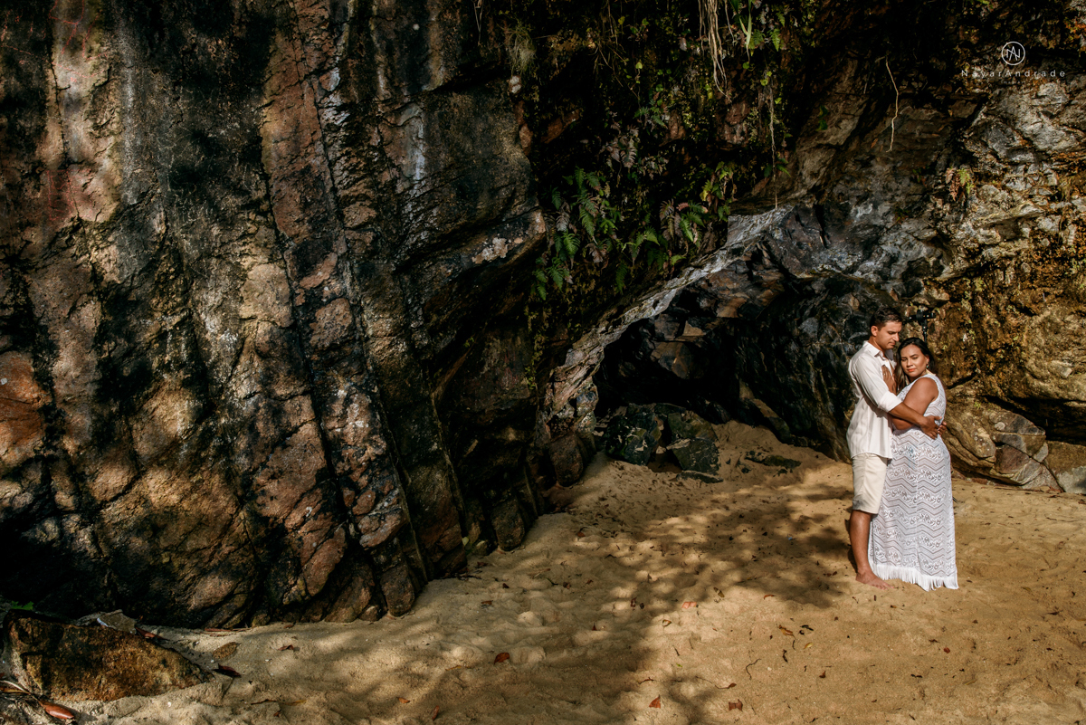 ensaio pre casamento na praia de ubatuba em sao paulo casal de blusa branca com fotos nas pedras e na agua cristalina
