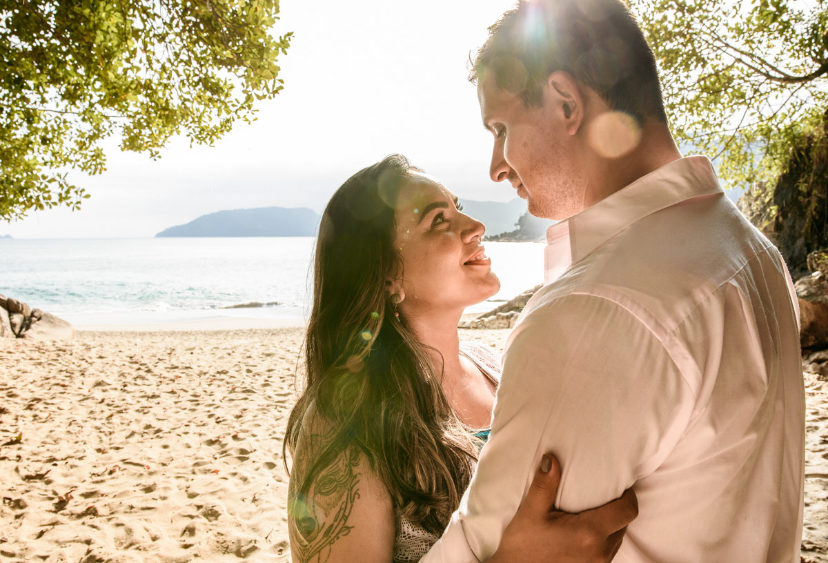 ensaio pre casamento na praia de ubatuba em sao paulo casal de blusa branca com fotos nas pedras e na agua cristalina