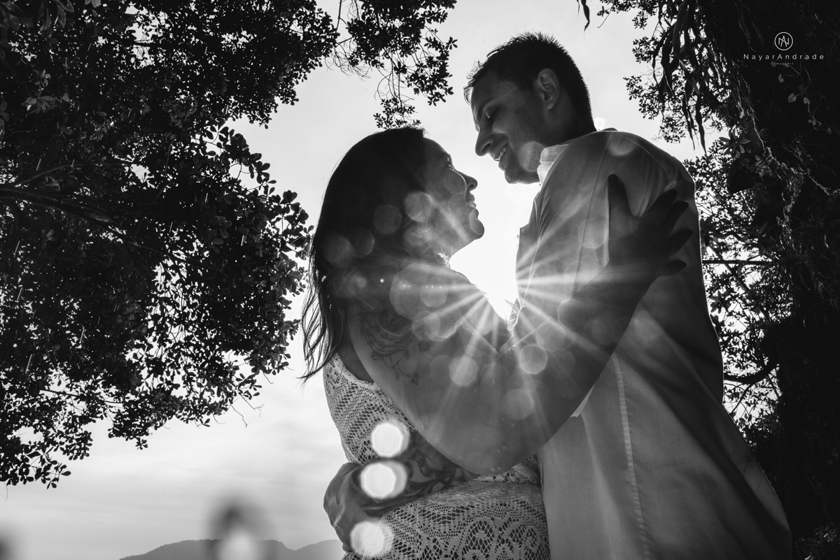 ensaio pre casamento na praia de ubatuba em sao paulo casal de blusa branca com fotos nas pedras e na agua cristalina