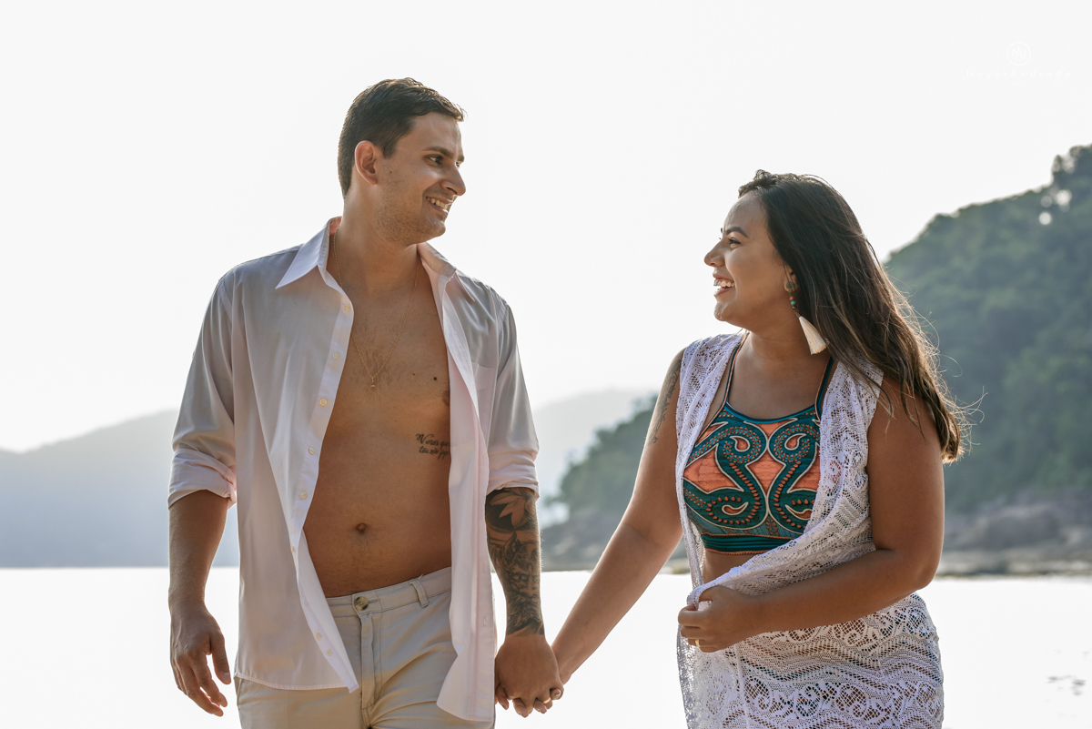 ensaio pre casamento na praia de ubatuba em sao paulo casal de blusa branca com fotos nas pedras e na agua cristalina
