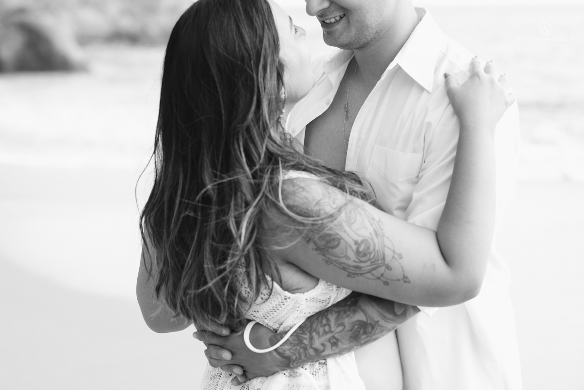 ensaio pre casamento na praia de ubatuba em sao paulo casal de blusa branca com fotos nas pedras e na agua cristalina
