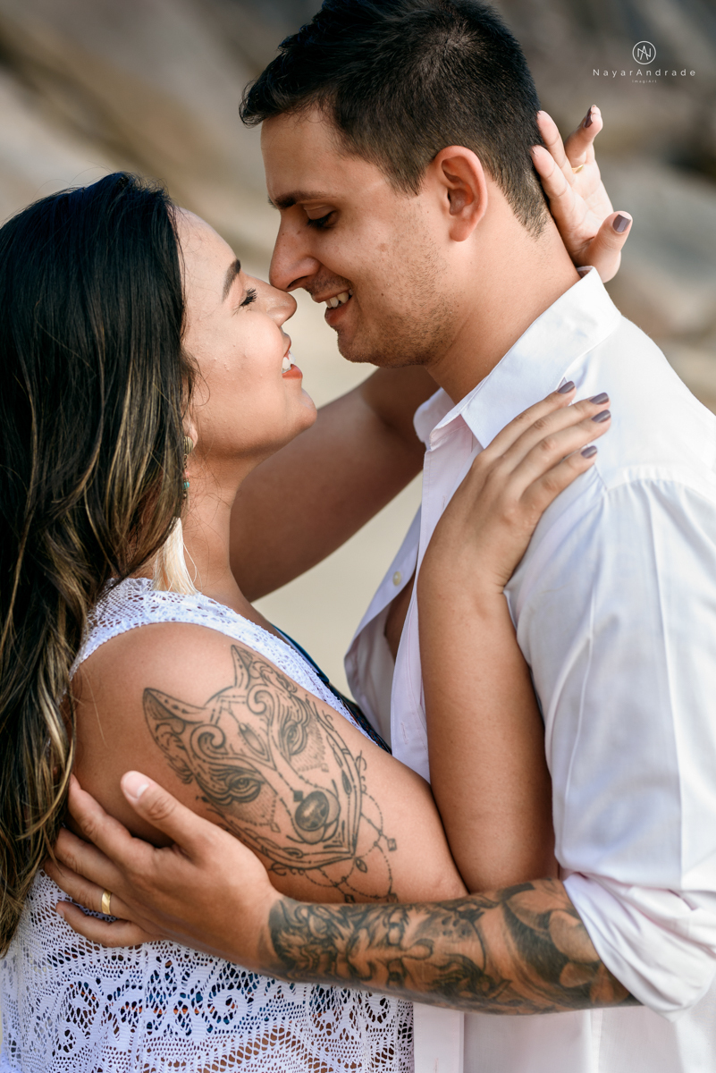 ensaio pre casamento na praia de ubatuba em sao paulo casal de blusa branca com fotos nas pedras e na agua cristalina