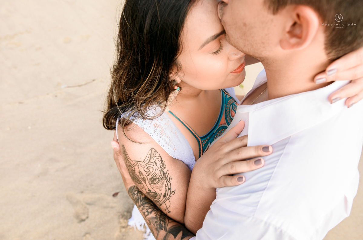 ensaio pre casamento na praia de ubatuba em sao paulo casal de blusa branca com fotos nas pedras e na agua cristalina