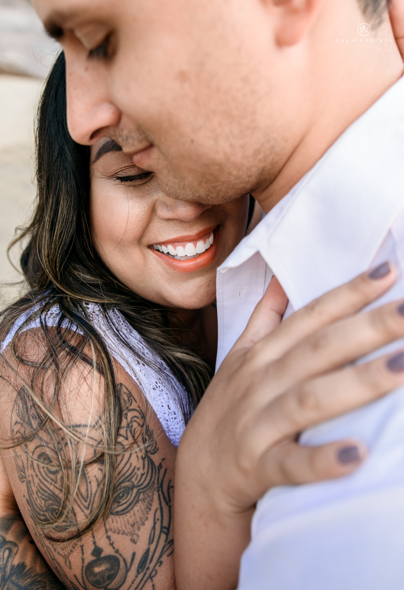 ensaio pre casamento na praia de ubatuba em sao paulo casal de blusa branca com fotos nas pedras e na agua cristalina