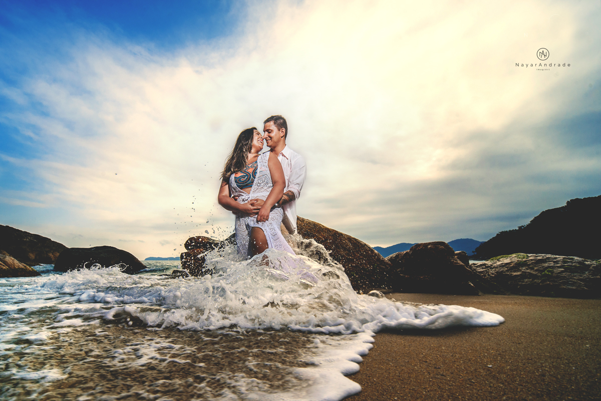 ensaio pre casamento na praia de ubatuba em sao paulo casal de blusa branca com fotos nas pedras e na agua cristalina