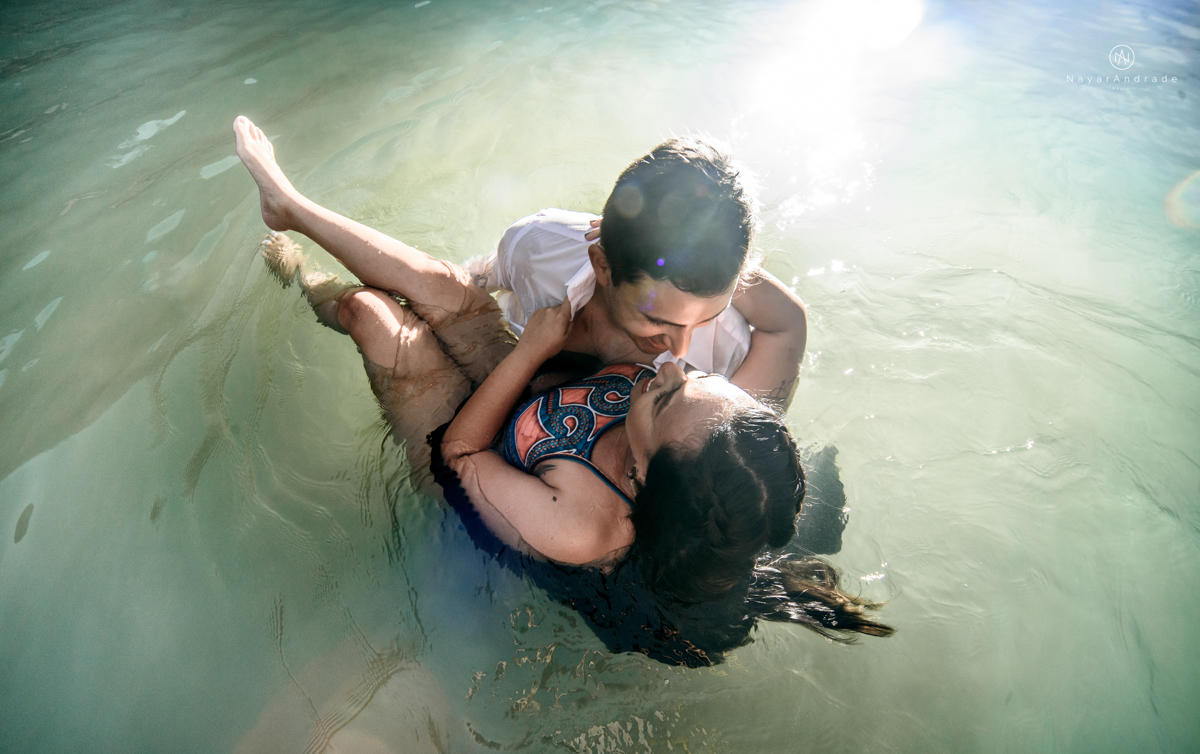 ensaio pre casamento na praia de ubatuba em sao paulo casal de blusa branca com fotos nas pedras e na agua cristalina