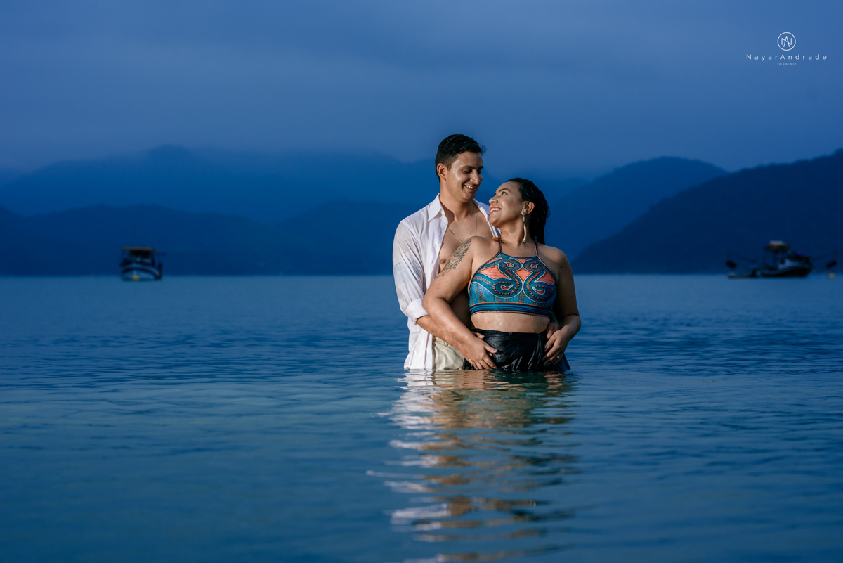 ensaio pre casamento na praia de ubatuba em sao paulo casal de blusa branca com fotos nas pedras e na agua cristalina