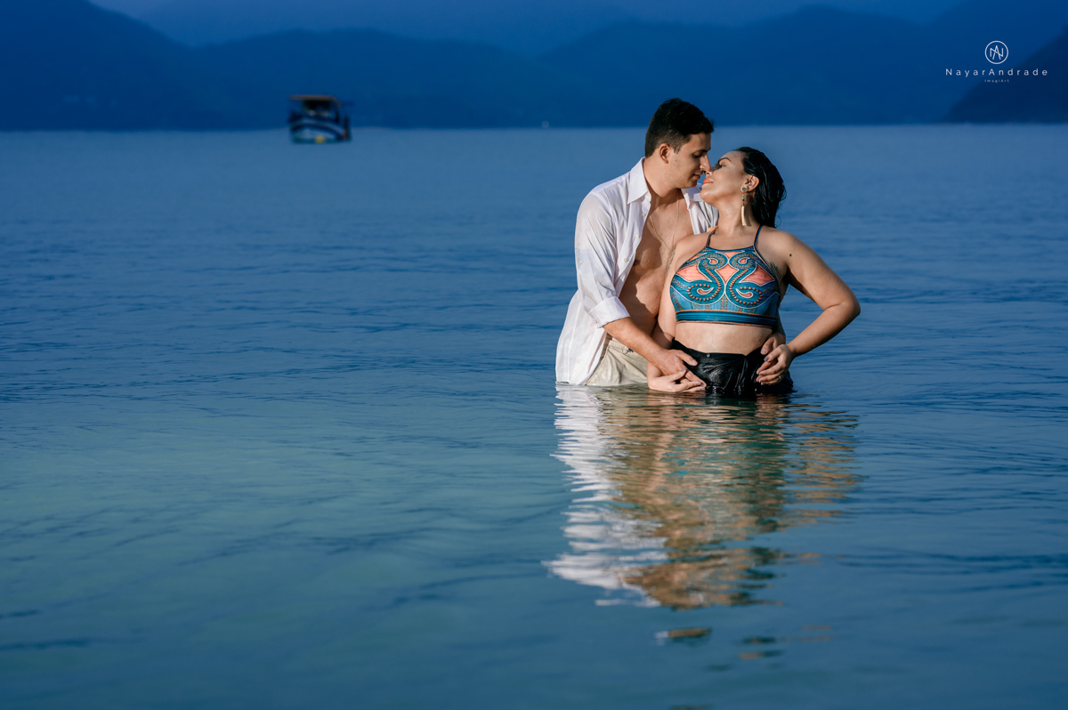 ensaio pre casamento na praia de ubatuba em sao paulo casal de blusa branca com fotos nas pedras e na agua cristalina