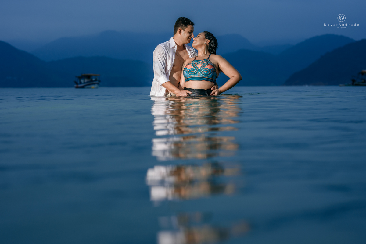 ensaio pre casamento na praia de ubatuba em sao paulo casal de blusa branca com fotos nas pedras e na agua cristalina