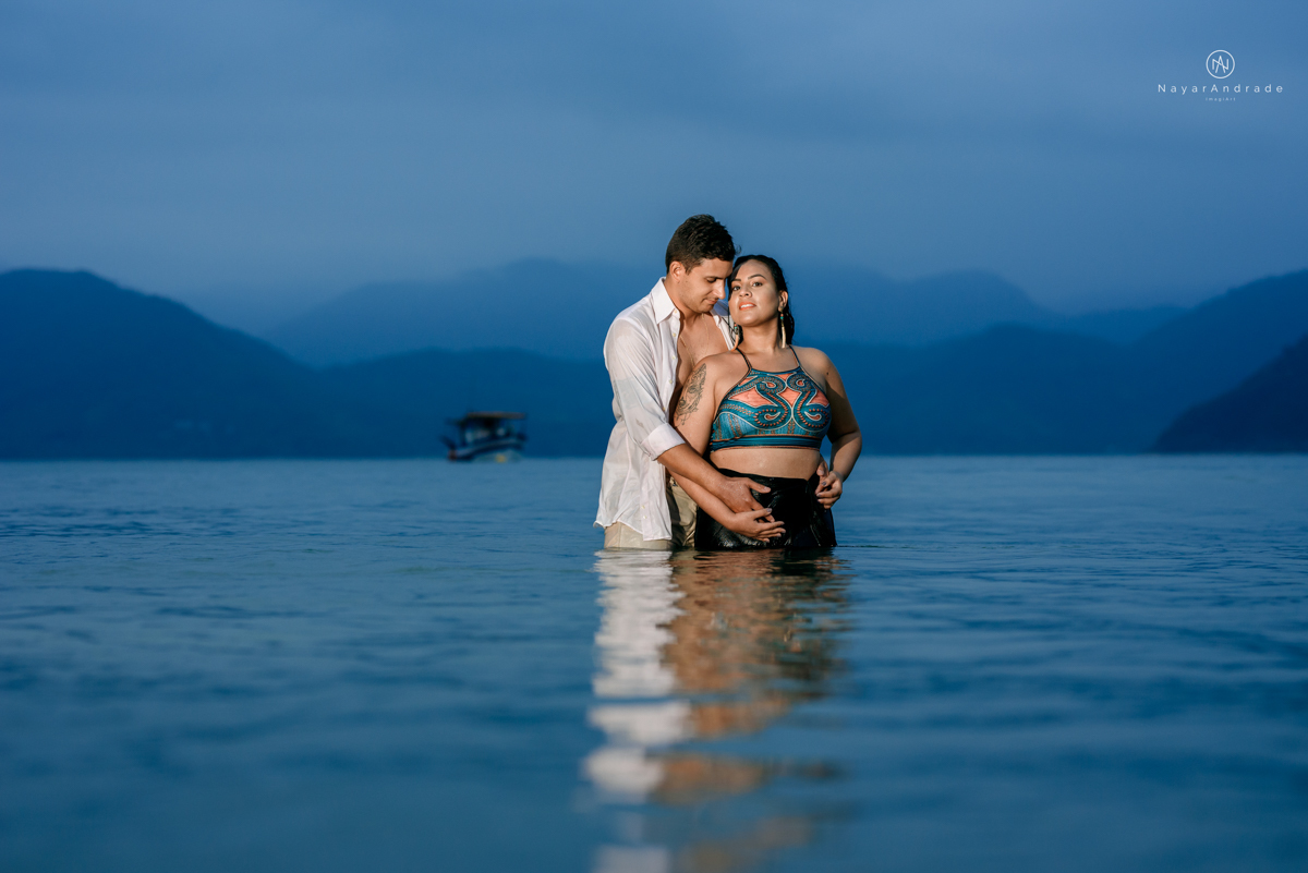 ensaio pre casamento na praia de ubatuba em sao paulo casal de blusa branca com fotos nas pedras e na agua cristalina