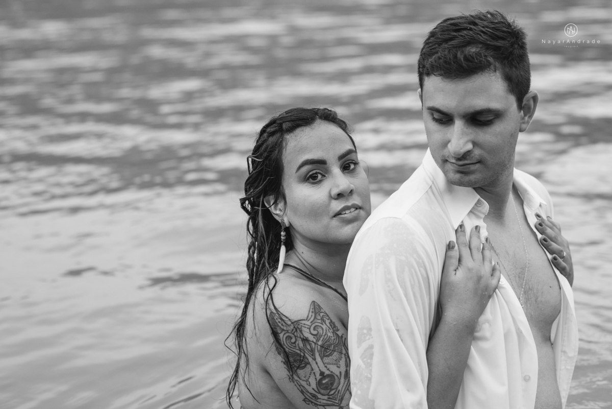 ensaio pre casamento na praia de ubatuba em sao paulo casal de blusa branca com fotos nas pedras e na agua cristalina