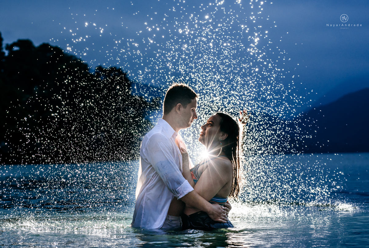 ensaio pre casamento na praia de ubatuba em sao paulo casal de blusa branca com fotos nas pedras e na agua cristalina