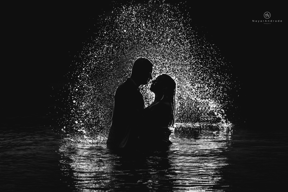 ensaio pre casamento na praia de ubatuba em sao paulo casal de blusa branca com fotos nas pedras e na agua cristalina