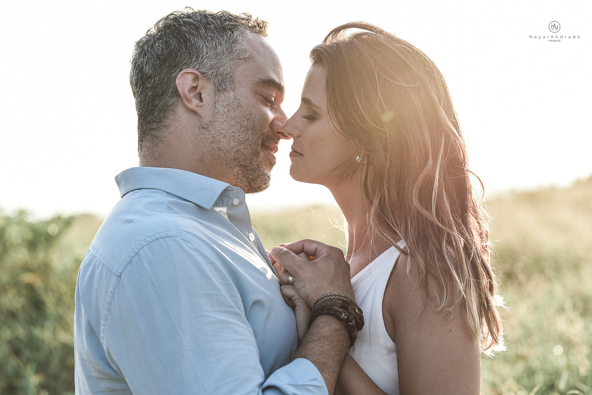 ensaio feito no fim de tarde na praia com a golden hour lindos raios de sol e luz natural casal romantico e apaixonado