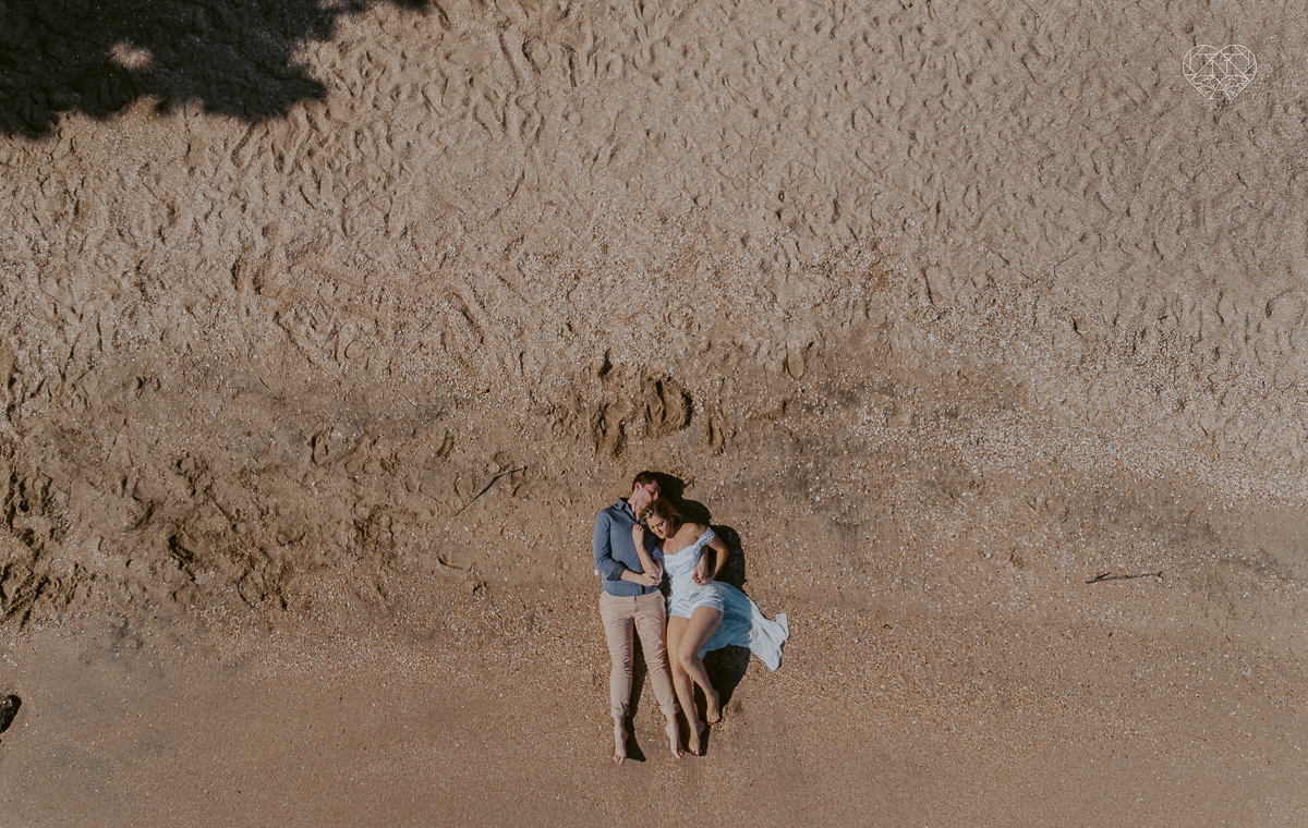 ensaio pre casamento pre wedding na praia das conchas no guaruja noiva de roupa branca e buque e noivo com roupa sociall fotos feitas na agua  na grama e correndo nas pedras ensaio feito pela fotografa premiada nayara andrade de santos