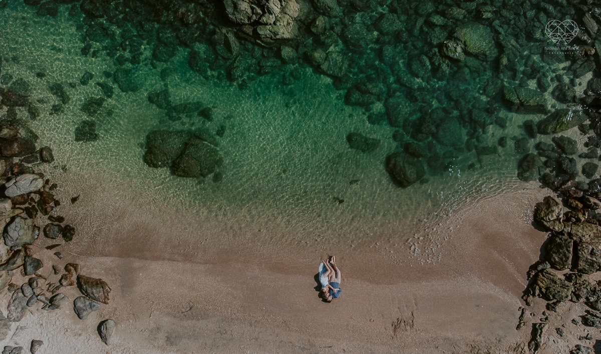 ensaio pre casamento pre wedding na praia das conchas no guaruja noiva de roupa branca e buque e noivo com roupa sociall fotos feitas na agua  na grama e correndo nas pedras ensaio feito pela fotografa premiada nayara andrade de santos